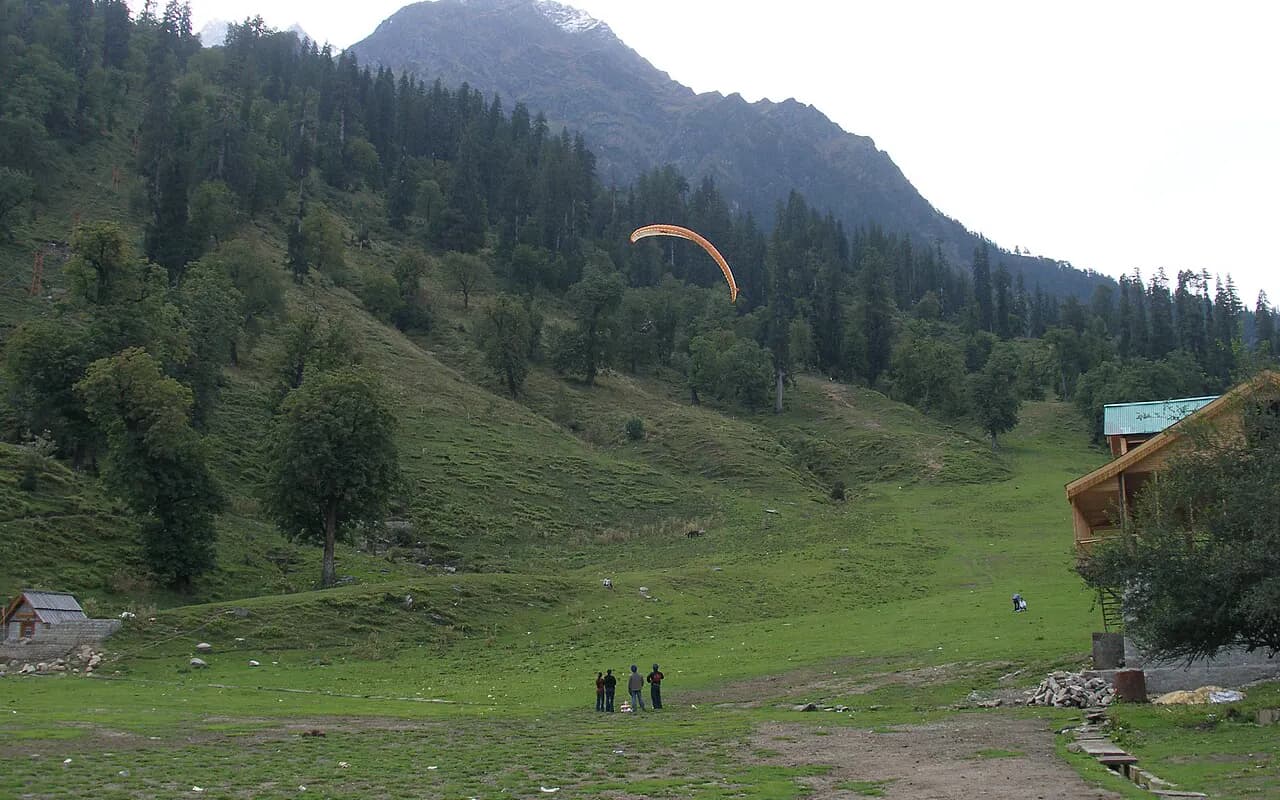 Paraglider over Solang Valley's meadows