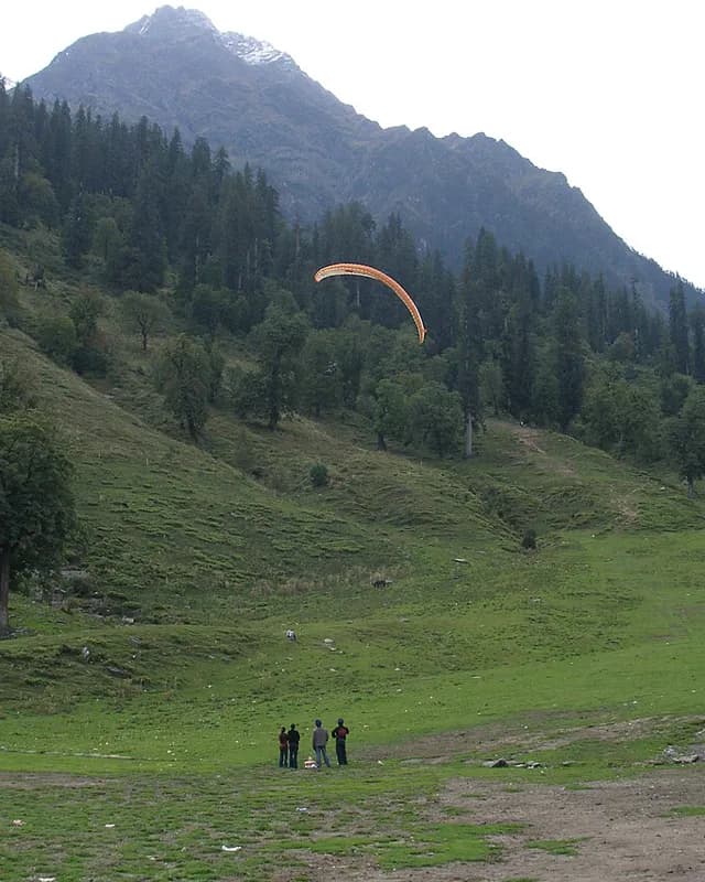 Paraglider over Solang Valley's meadows
